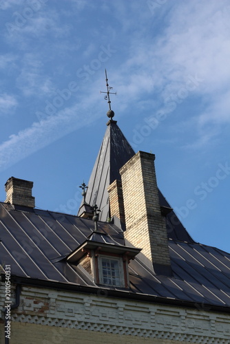 Doles Manor House, Latvia. Historic manor roof detail on a sunny day. Warm sunlight highlights aged roof tiles and traditional architecture, showcasing heritage, texture, and timeless European country