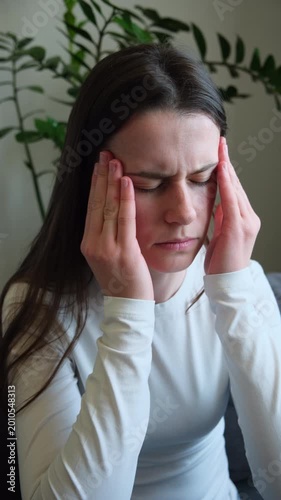 Sad woman head pain ache discomfort migraine overworked exhausted frustrated loneliness anxiety worried problem. Tired young female unwell stress headache suffer depression sitting on couch at home