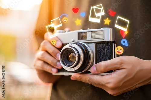 Person holding camera with social media icons and emojis floating around  photography concept