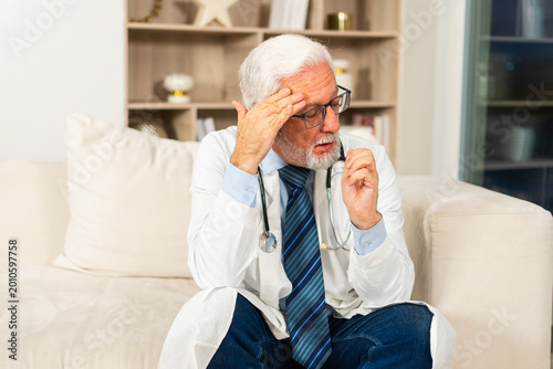 Photos Sad tired mature senior male doctor in medical uniform in hospital or doctor office