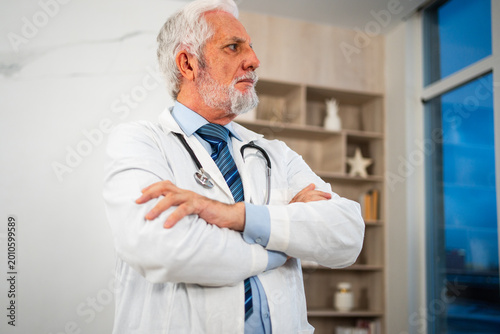Schilderij op canvas Mature senior male doctor in glasses medical uniform in hospital or doctor office