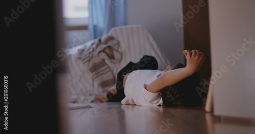 Foto Child stretched out on floor beside bed, looking disengaged and uninterested, sh