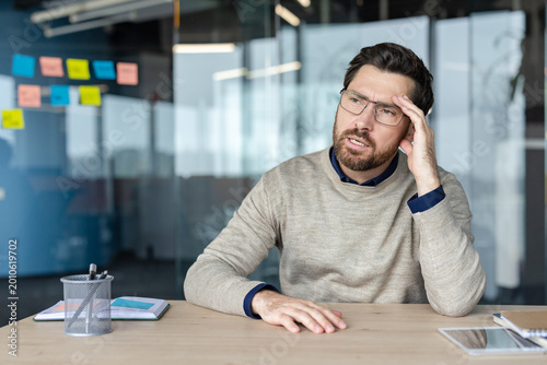 Εκτύπωση καμβά Worried professional man experiencing stress and a painful headache while sittin