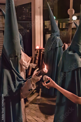 Konstfotografi penitentes de una hermandad dandole cera de los cirios a niños para hacer bolas