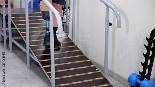 Amputee man with prosthetic leg walking down ramp for rehabilitation