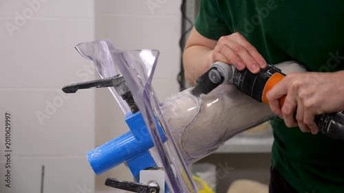 Prosthetic technician cutting custom leg socket with power tool