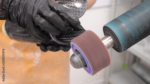 Worker sanding a carbon fiber part on a grinding machine