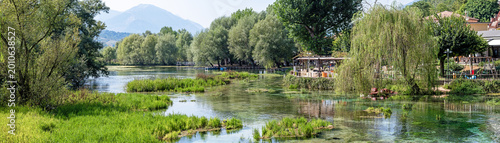 Foto Panoramic view of Posta Fibreno lake in Frosinone, Lazio, Italy in late August, with crystal-clear waters, lush vegetation, and the Apennine Mountains creating a serene and vibrant natural landscape
