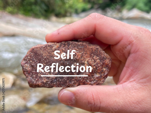 Self reflection concept with engraved stone in hand by the river.
