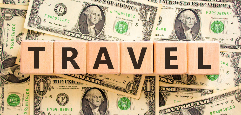 Obraz premium Travel traveling touristic word symbol. Concept word Travel on beautiful blocks. Beautiful dollar bills background. Beautiful dollar bills. Business travel traveling touristic word concept. Copy space
