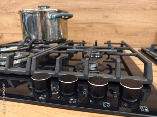 фотографія Four burner black built in gas cooker close up showing control knobs and metal p