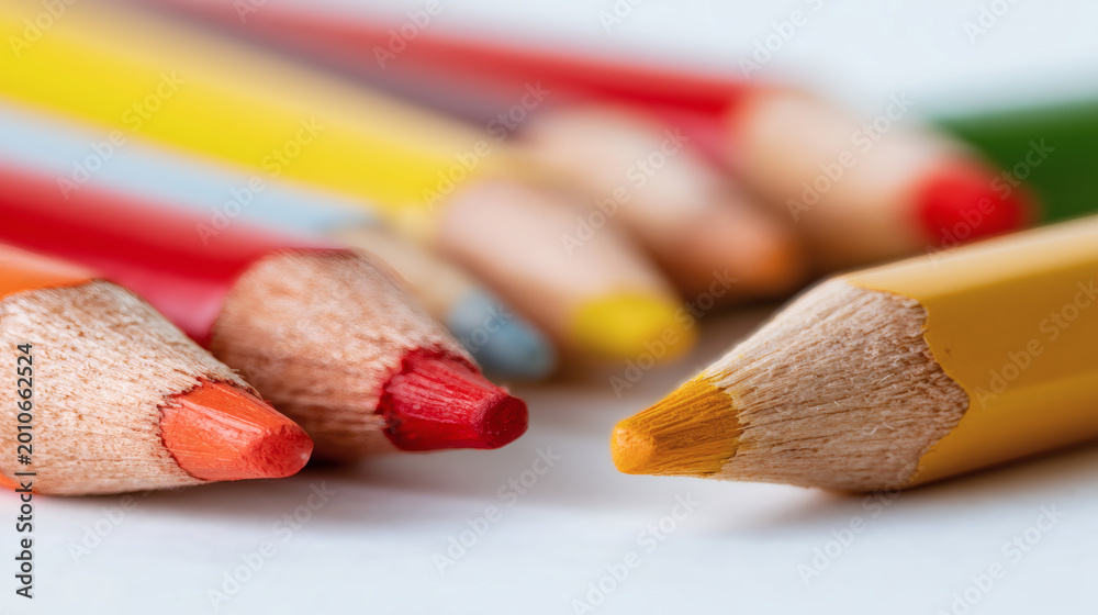 Obraz premium Macro photography showing sharpened colored pencils resting over white surface. Bright colorful drawing tools creating diagonal composition. Creative educational background providing empty space