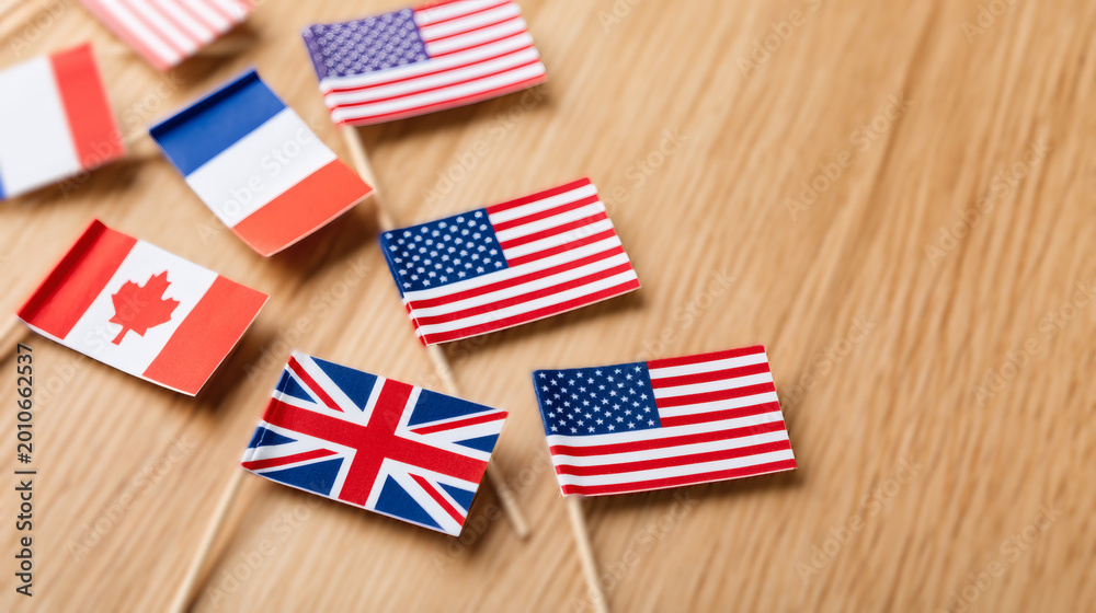 Obraz premium Handmade paper international flags scattered over clean light oak wooden desk. Creative children educational craft showing global unity concept. Flat lay background providing massive empty copy space