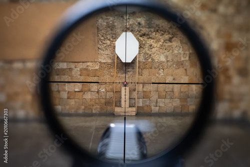Tableau sur toile Close-up view through a rifle scope at an indoor shooting range, with the crossh
