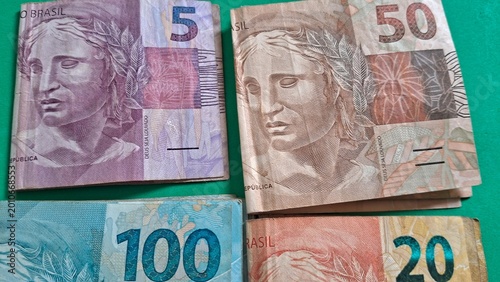 Obraz na plátně Brazilian banknotes featuring various denominations displayed on a solid green b