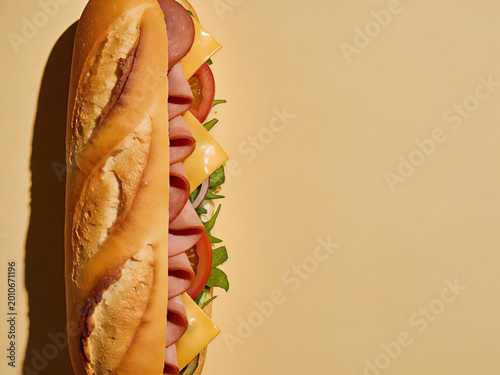 Vertical hoagie sandwich with ham cheese and vegetables on clean background with copy space