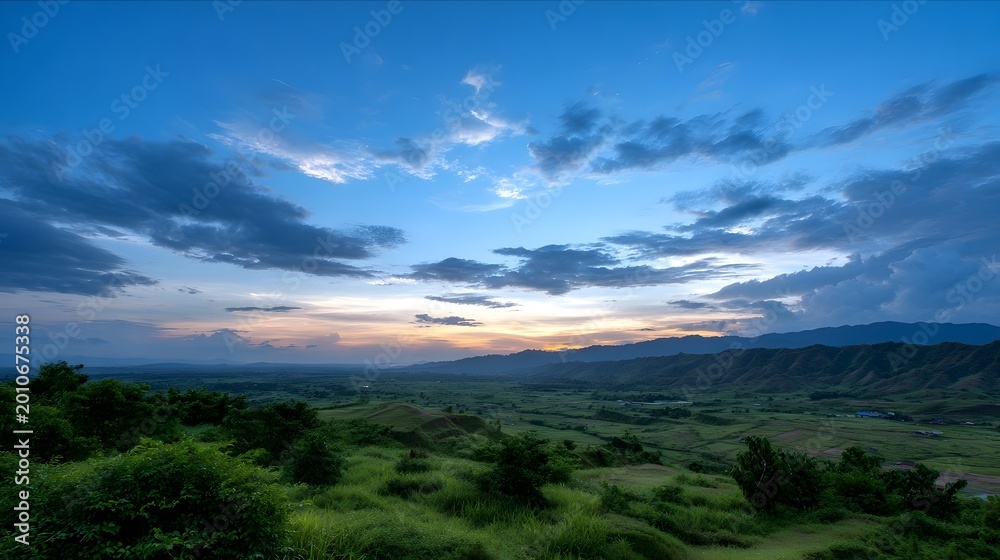 Fototapeta premium Panoramic view of lush green valleys and rolling mountains bathed in the soft ethereal light of dawn or dusk