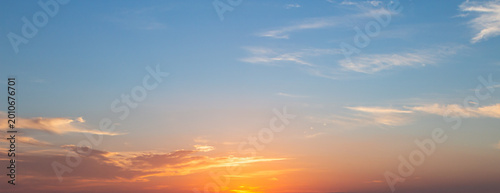 Panoramic sunset sky background with vibrant orange and golden clouds under a soft blue twilight sky