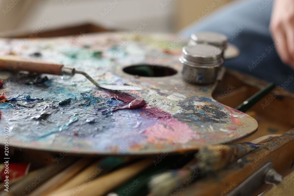 Fototapeta premium Woman with paints, palette, brushes and knife indoors, closeup