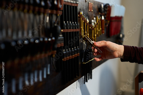 Принти на полотні Artisan selecting a tool from an organized workshop wall in a traditional leathercraft atelier