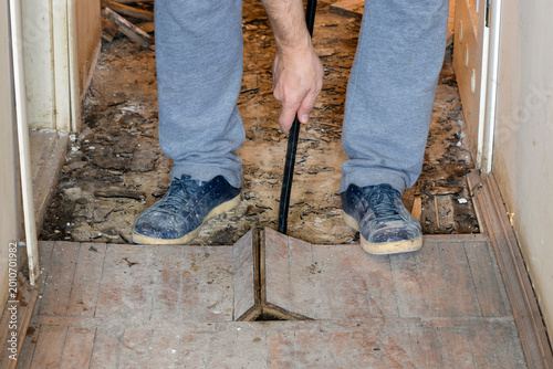 A man is dismantling old wooden parquet.