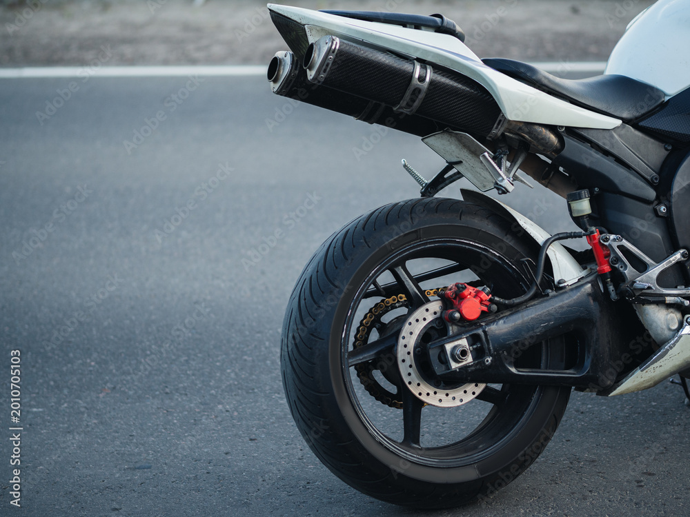 Obraz premium The back of a sports bike on the road. The wheel and exhaust system . Copy space