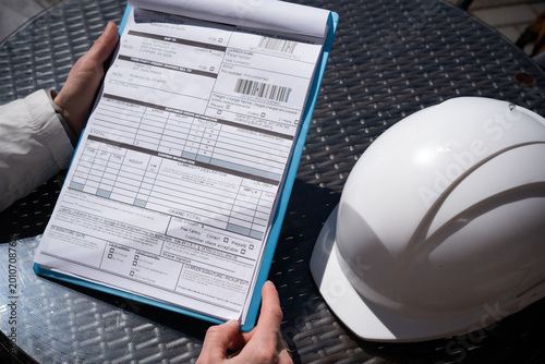 Cuadro en lienzo The worker holds a tablet with documents or bill of lading a protective helmet