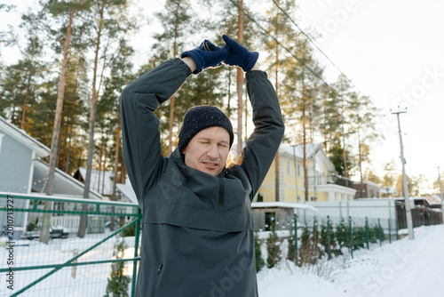 Картината върху платно A middle-aged man performs an upward stretch outdoors