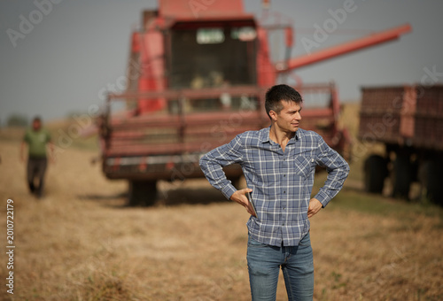 Schilderij op canvas Farmer standing in front of combine harvester