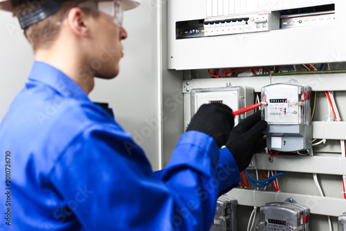 Quadro su tela Electrician with screwdriver checking electrical meter indoors, closeup