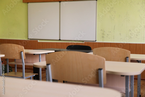 Fotografie Wooden desks, chairs and whiteboard in classroom at school, closeup