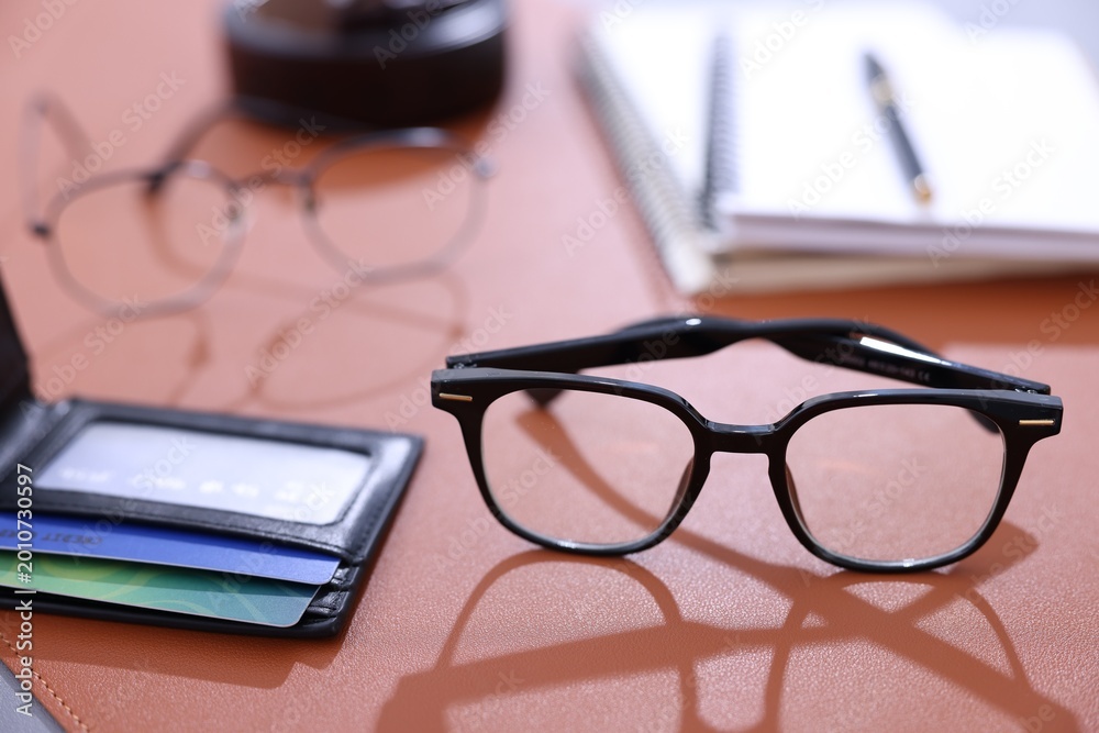 Fototapeta premium Stylish glasses and personal belongings on brown table, closeup