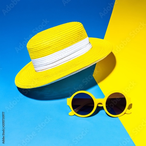 Bright Yellow Straw Hat and Round Sunglasses on Blue and Yellow Background