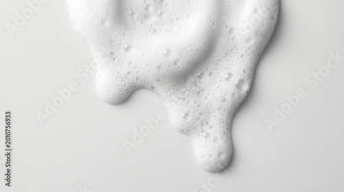 фотографія White cleansing foam with bubbles dripping on a light background for skincare product texture