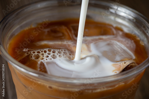 Cream poured into iced coffee drink