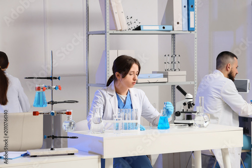 Young chemists with different glassware examining water samples in laboratory