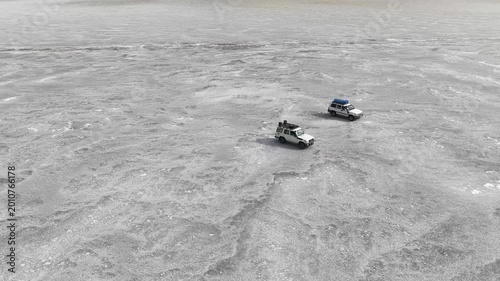 Aerial view of off-road vehicles parked on the vast white salt crust of the Danakil Desert under bright light in Dalol, Afar, Ethiopia.