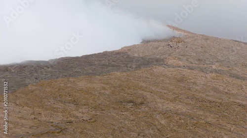 Aerial view of Erta Ale Volcano with thick white smoke rising from the crater and people standing on the rocky rim in Danakil Depression, Afar, Ethiopia.