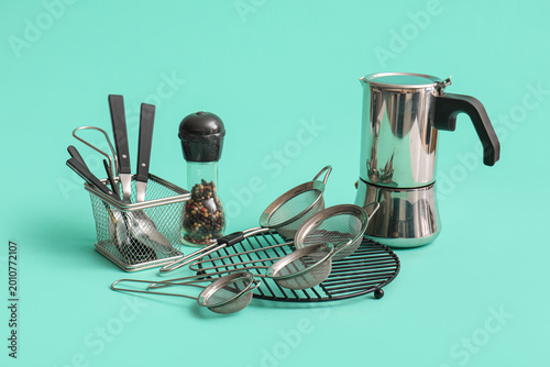 Valokuva Metal sieves with spoons and geyser coffee maker on turquoise background