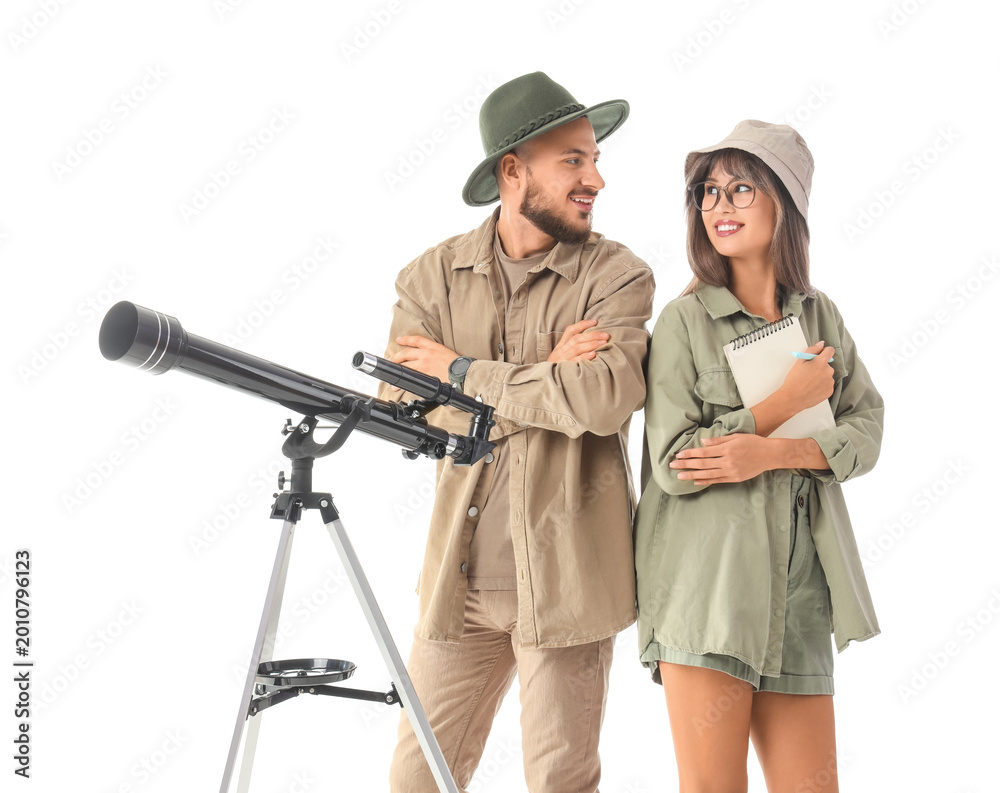 Fototapeta premium Young couple of travelers with telescope on white background