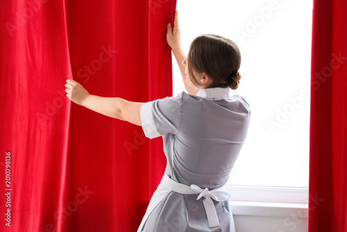 Young chambermaid adjusting...