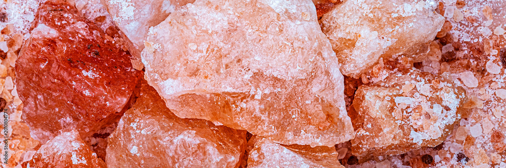 Fototapeta premium Large pieces of pink salt sit on a surface in a close-up view during daylight