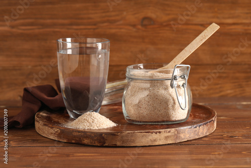 Photography Jar with psyllium husk powder and glass of water on wooden background