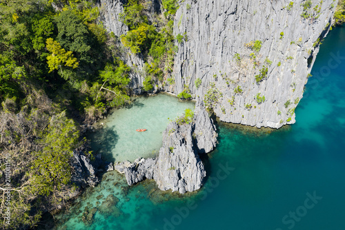 Kayakers explore Big Lagoon, found amid the scenic limestone islands of El Nido. This area in the Philippines is a popular vacation destination due to its beautiful coral reefs, beaches, and lagoons.