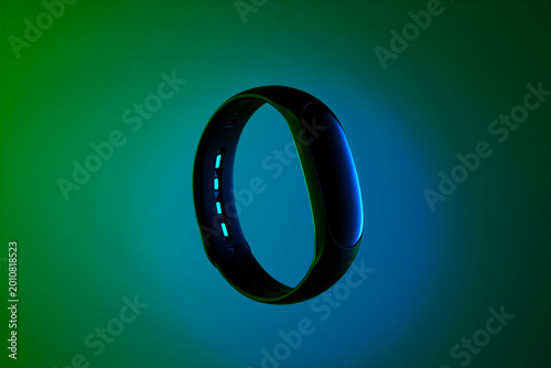 futuristic smart wristband glowing with neon blue lights on dark gradient background