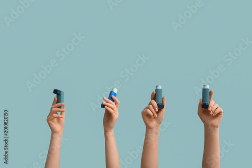 Photos Female hands with modern asthma inhalers on blue background
