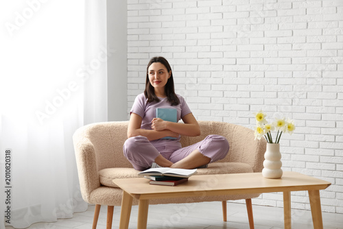 Young woman sitting on sofa...