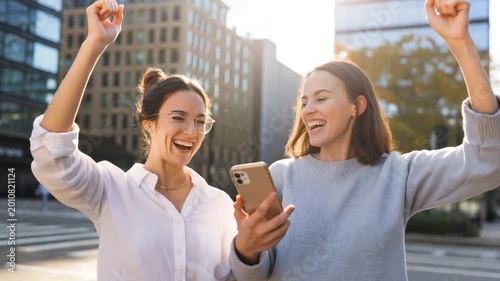 Excited young women celebrate great news while holding their smartphone in this dynamic and cheerful motion video clip