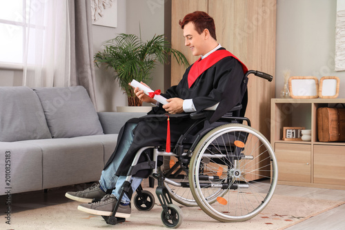 Male graduate in wheelchair with diploma at home