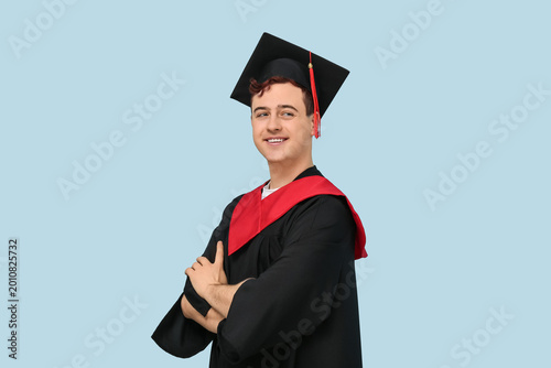 Happy male graduating student on blue background
